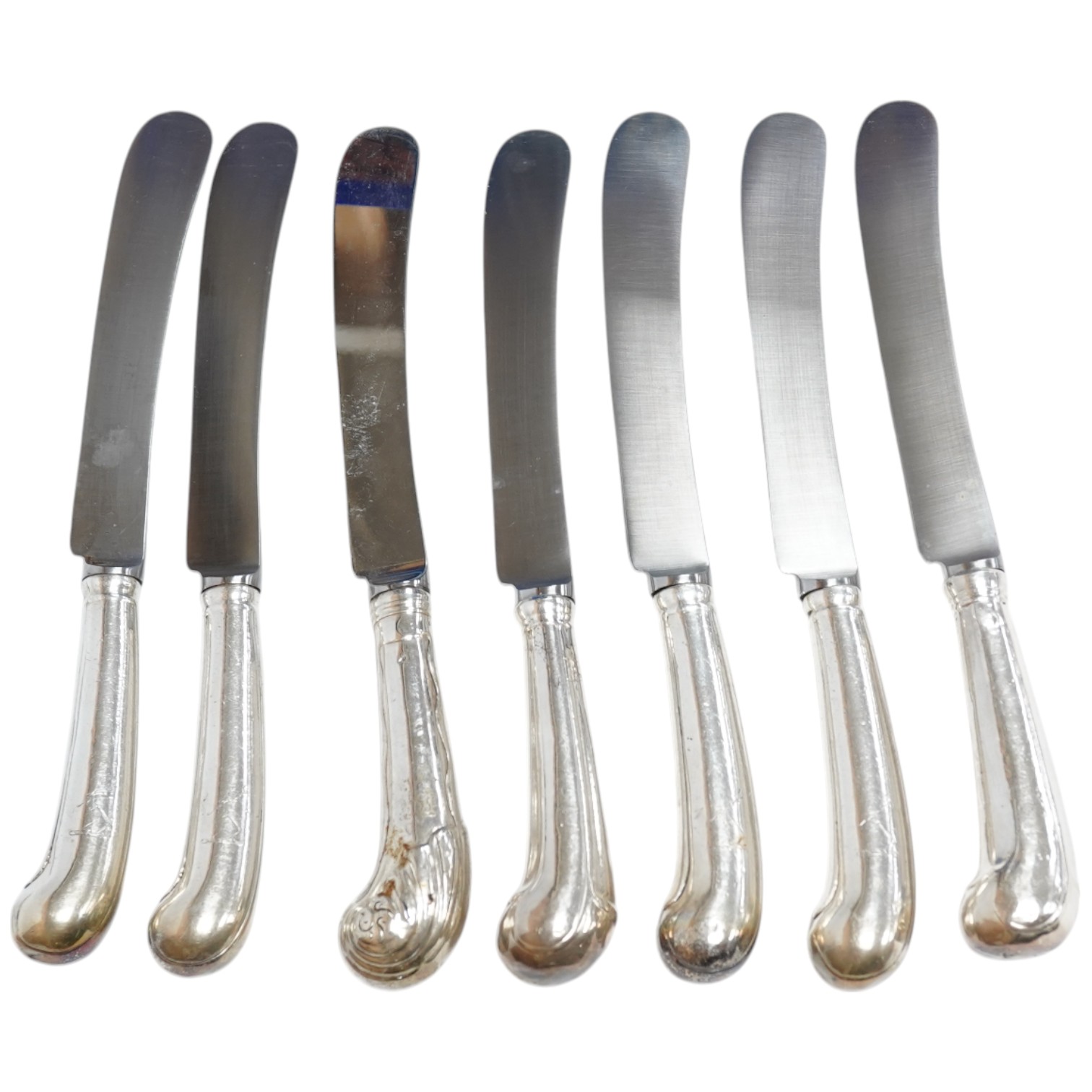A set of twelve Georgian loaded silver pistol grip table knives, with scroll decorated handles (re-bladed), 23.5cm, together with twelve other assorted 19th century white metal or silver handled dessert knives and eight